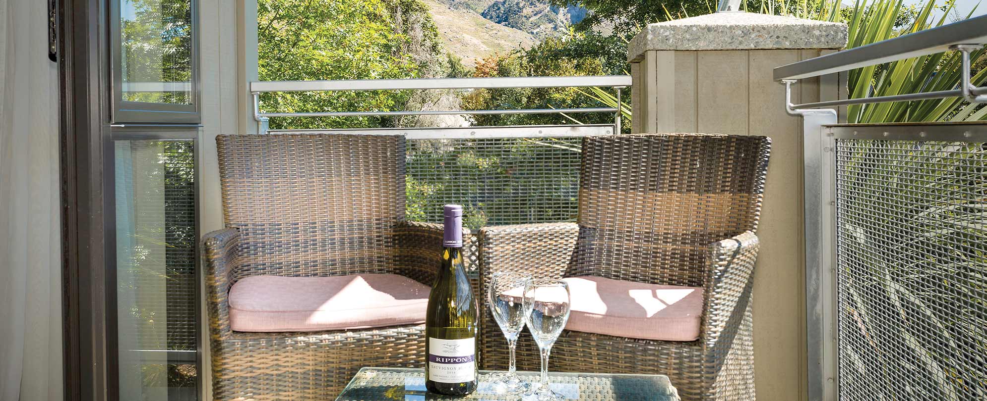 The standard suite balcony has two chairs and a table with a bottle of wine and two wine glasses.
