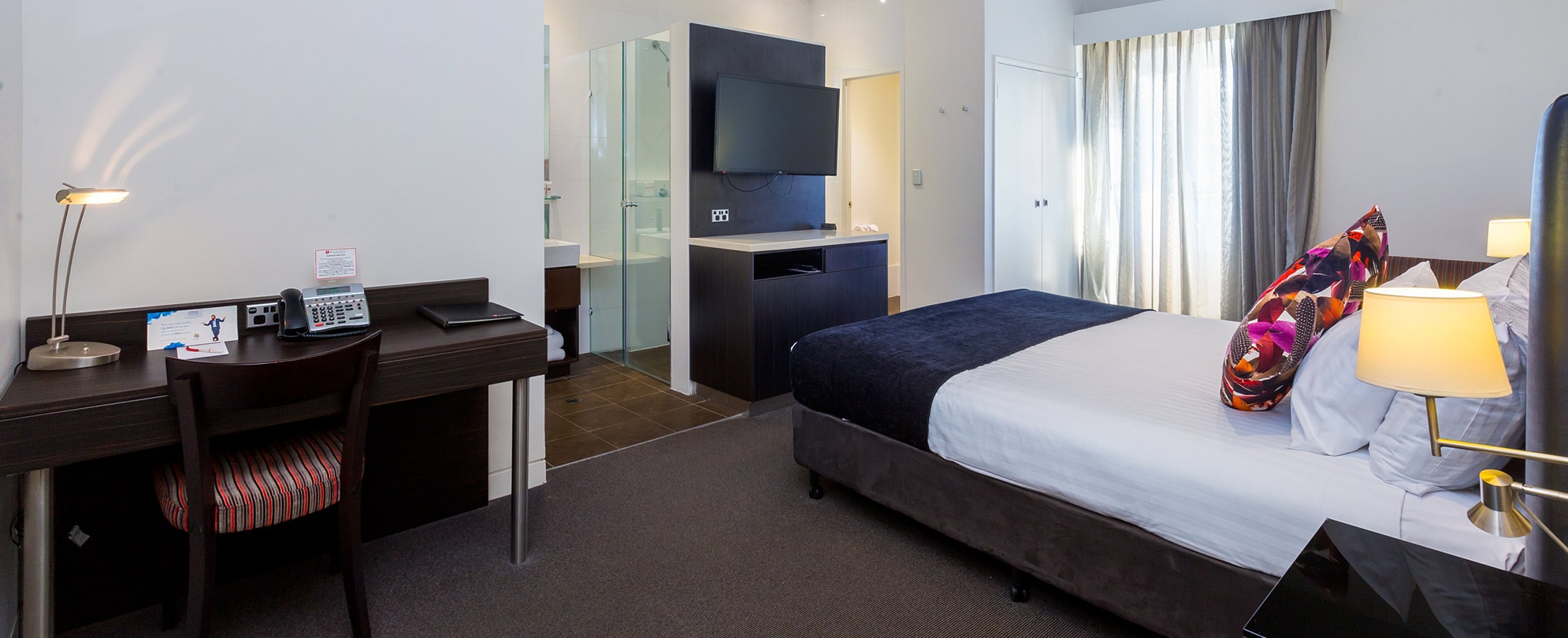 A desk, bed, and mounted tv inside a studio suite at Club Wyndham Perth