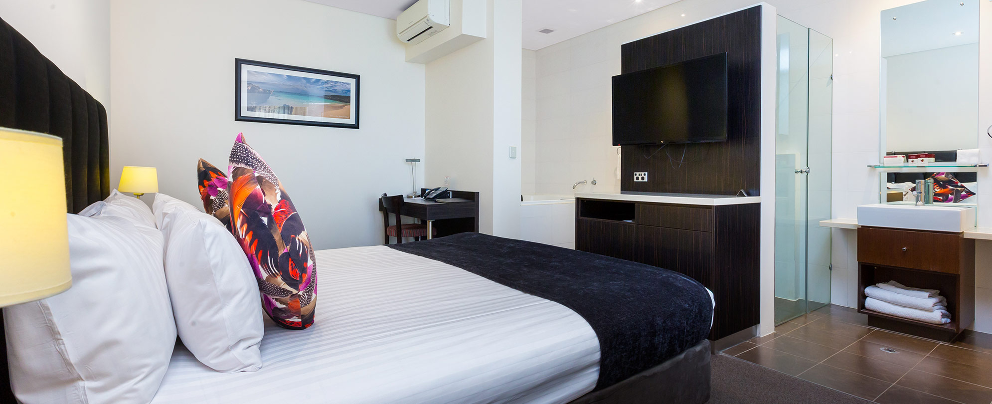 A made bed and mounted tv inside a studio suite at Club Wyndham Perth.