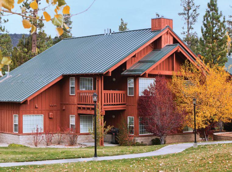 The exterior of WorldMark Big Bear, a cabin-style timeshare resort, surrounded by trees with autumn leaves.