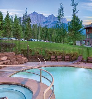 The outdoor pool and hot tub at WorldMark Canmore Banff, a timeshare resort, with the Canadian Rocky Mountains in the distance.