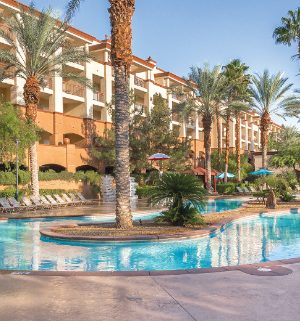 The outdoor pool and exterior of WorldMark Boulevard, surrounded by sun loungers and palm trees.
