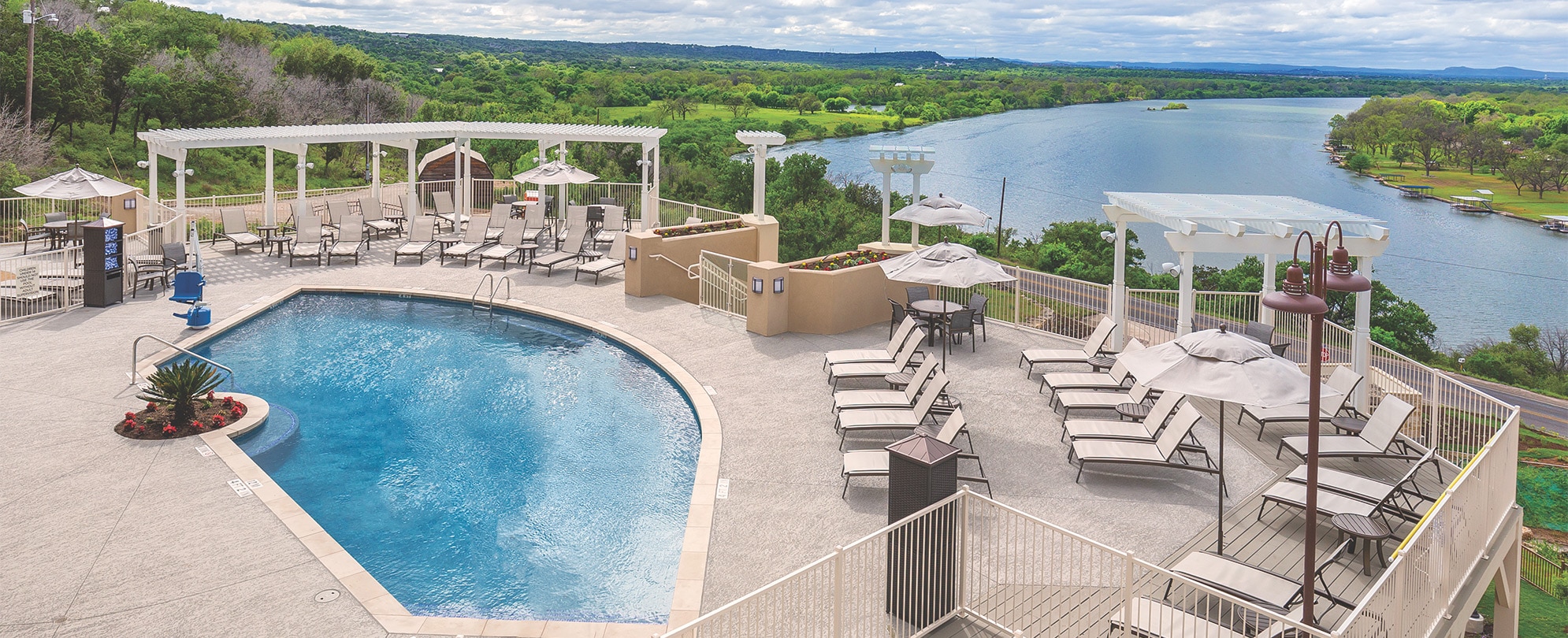 A pool surrounded by chairs overlooking a large body of water at WorldMark Marble Falls.