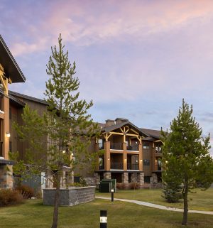 The exterior of a resort with trees and cloudy skies in Montana at the WorldMark West Yellowstone.