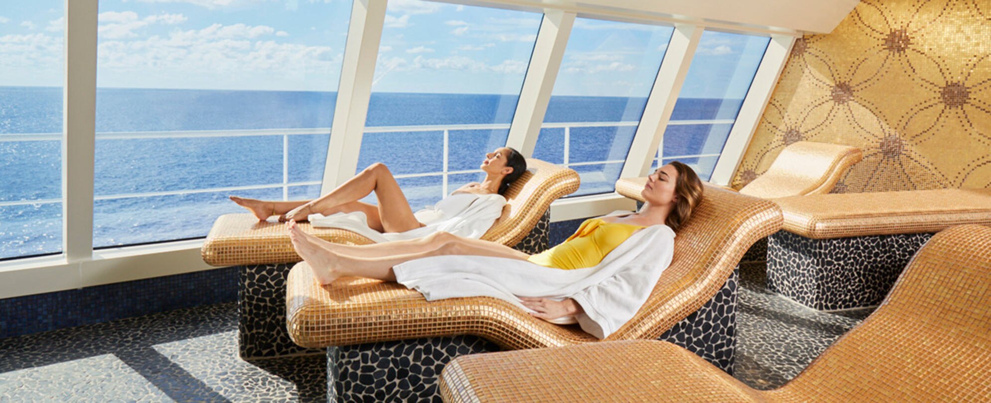 Two women lounging on a cruise ship overlooking the ocean on a Carnival cruise. 