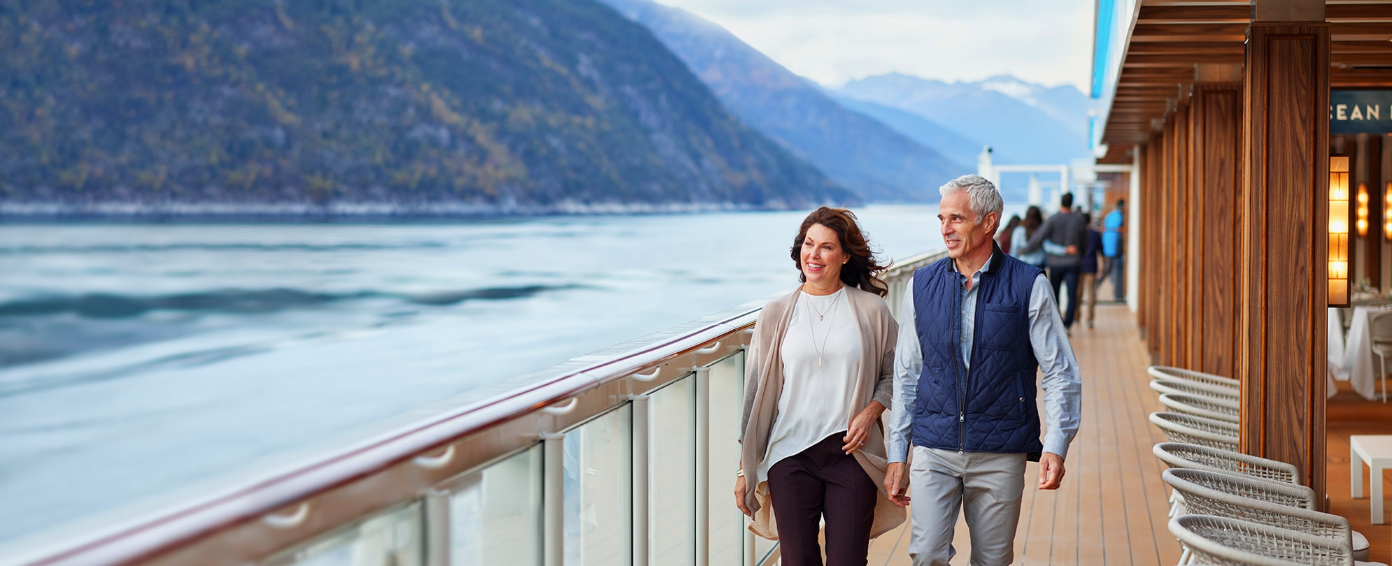 A man and woman on an Alaskan cruise walking and looking at the mountains in Alaska. 
