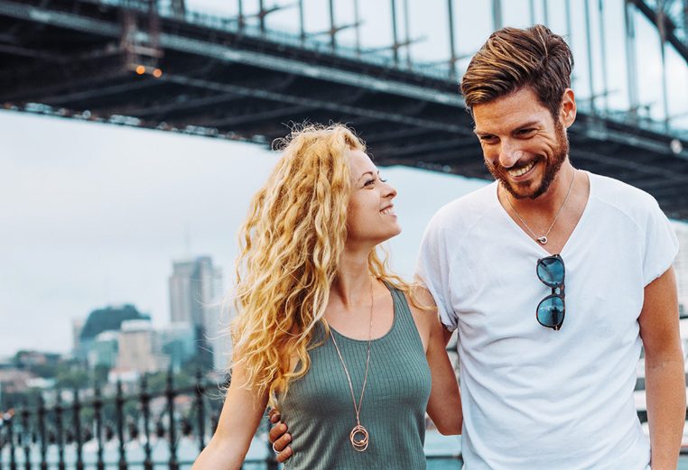 A smiling couple standing near a bridge in Australia, on a Worldmark by Wyndham tour.