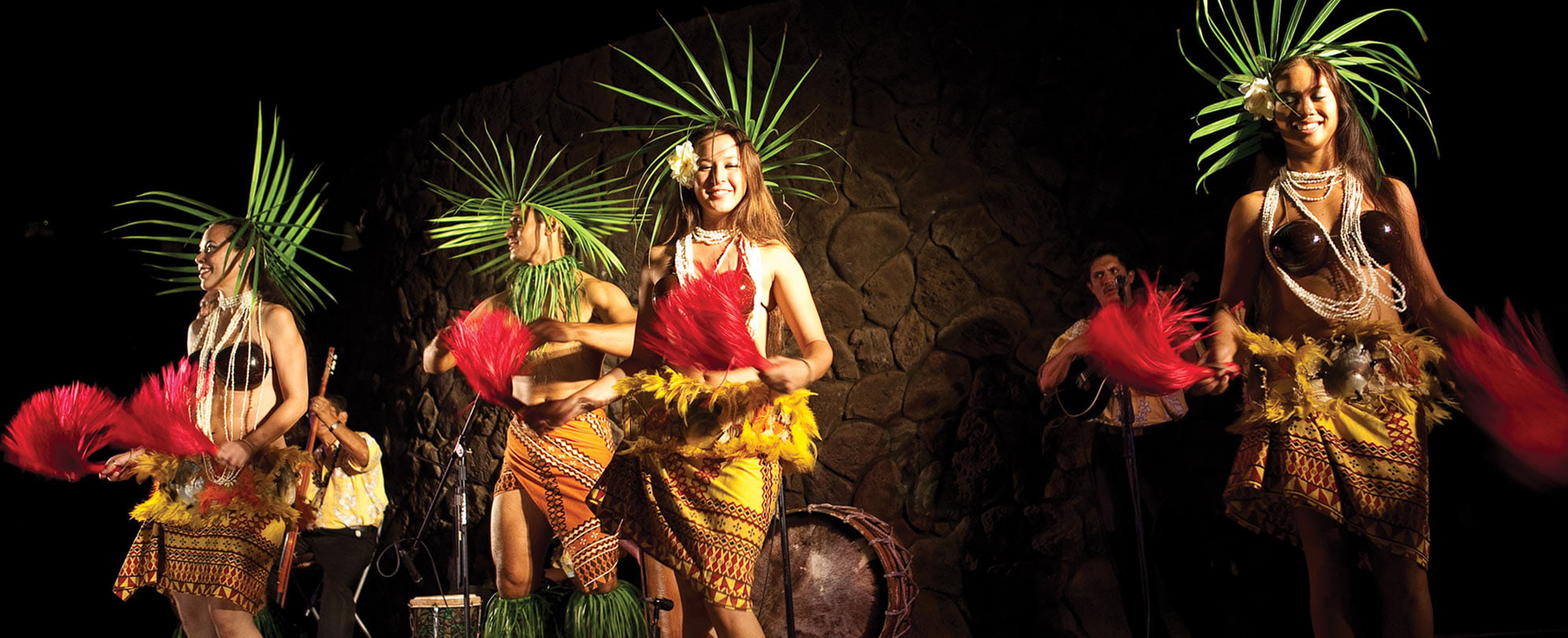 Luau performers wearing palm headdresses, coconut shells, and skirts. 