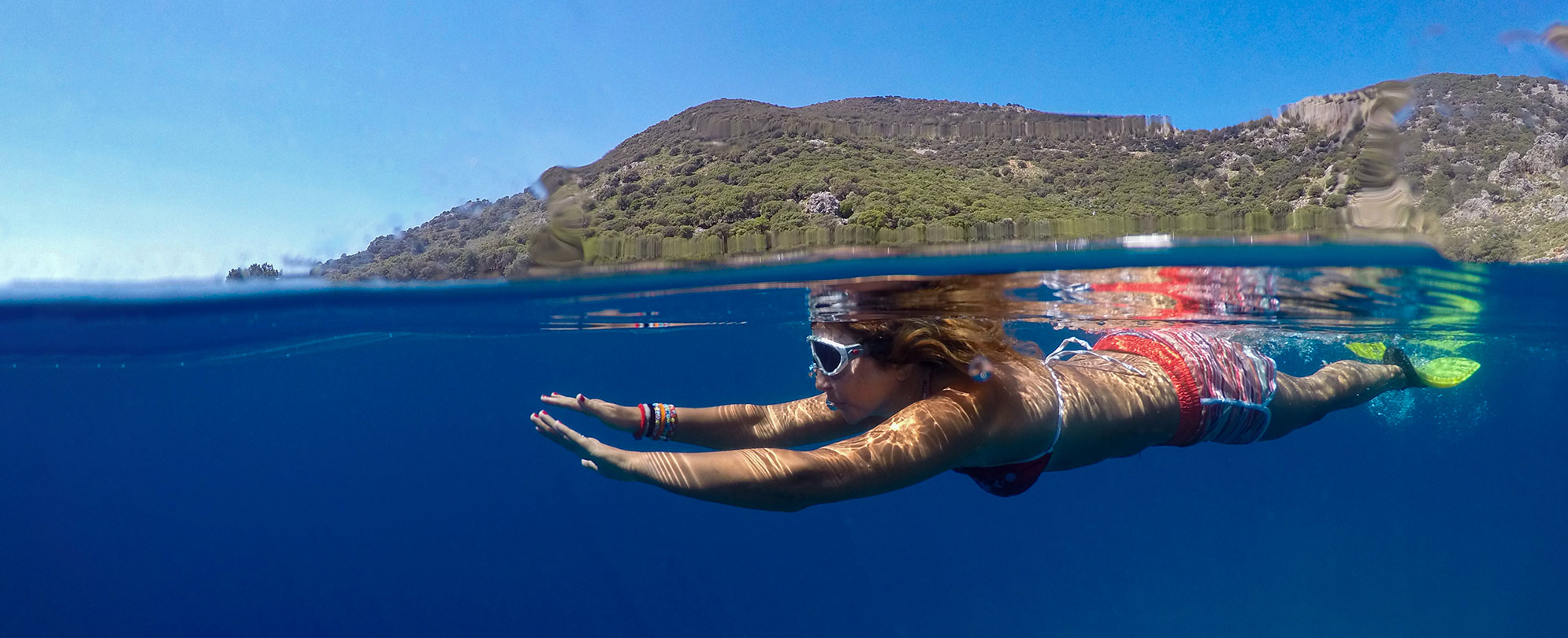 A woman swimming under water next to a small mountain range with WorldMark by Wyndham Western Caribbean cruise.
