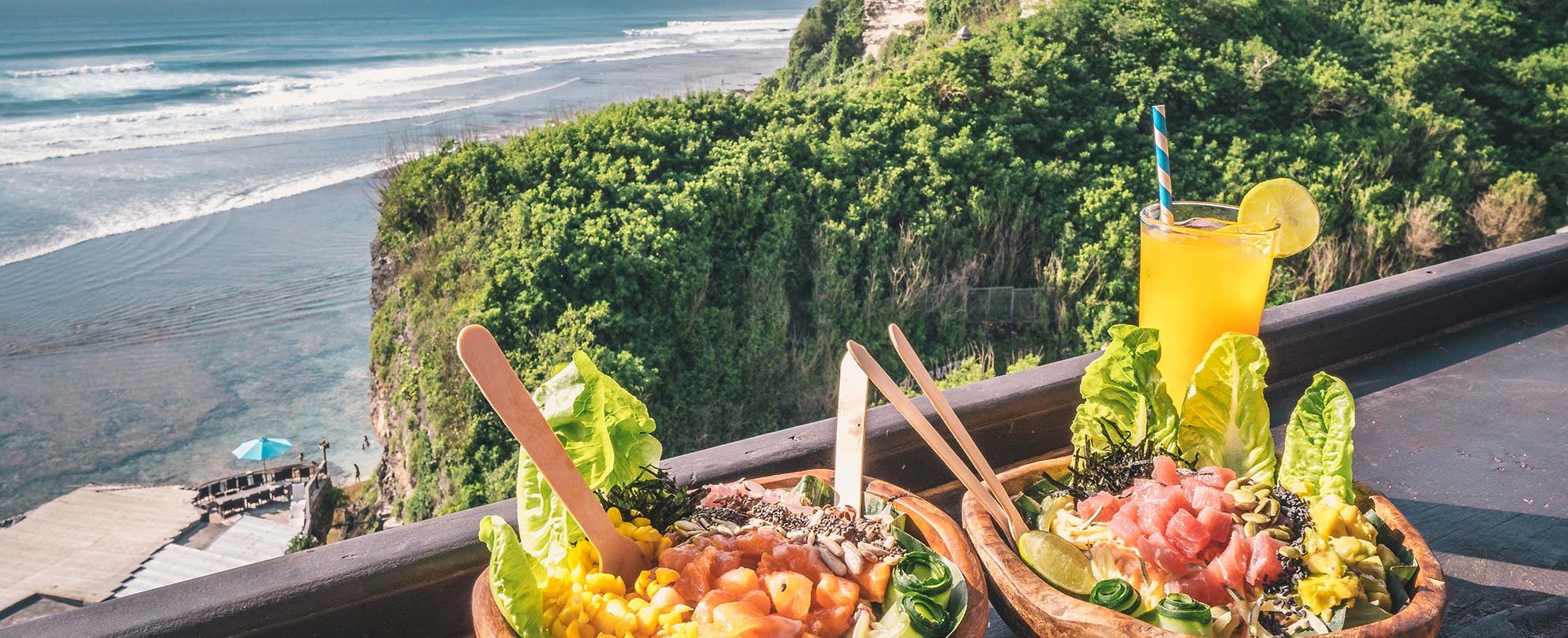 Poke bowls and a fruit drink on a bar overlooking the ocean in Baja, Mexico.