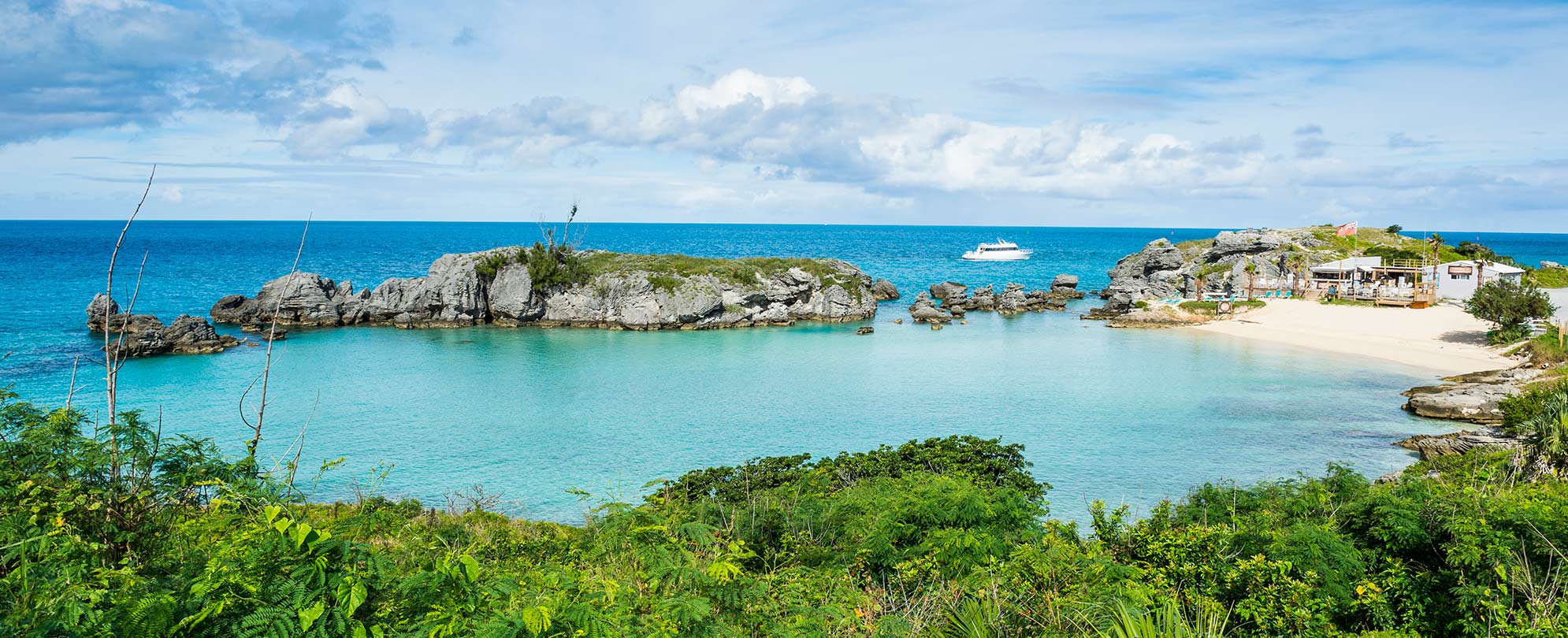 Beach destination with clear water surrounded by rocks and plants in Bermuda. 