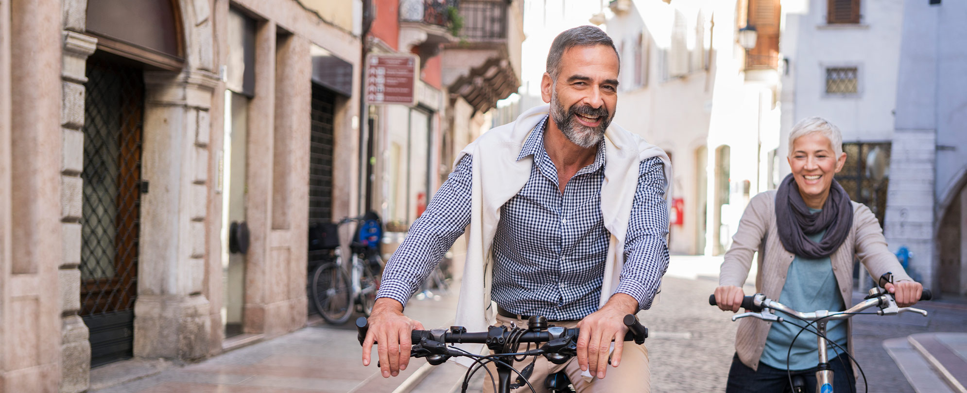 A smiling man and woman ride bikes through Italy during a WorldMark by Wyndham Travel Tour. 