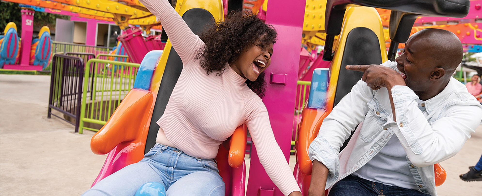 A man and woman smiling at each other while sitting on a carnival ride.