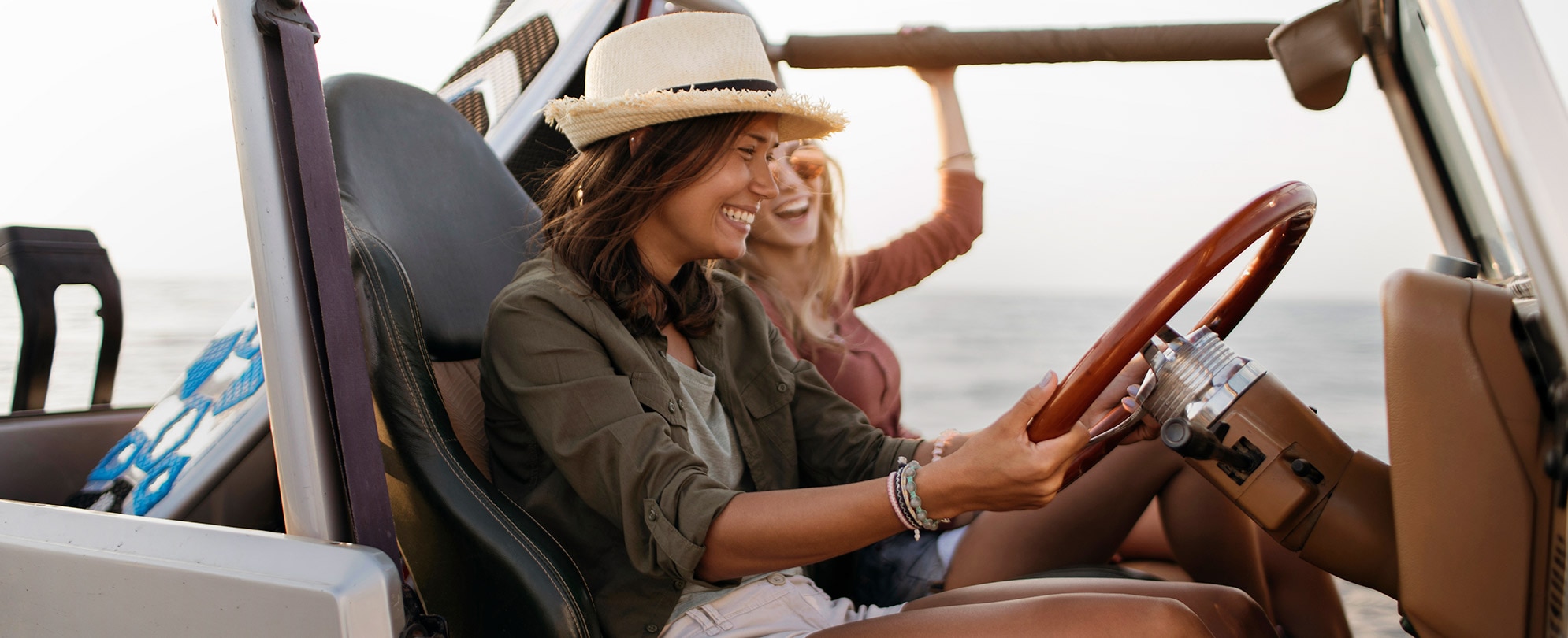 Two women driving a jeep, smiling and laughing. 