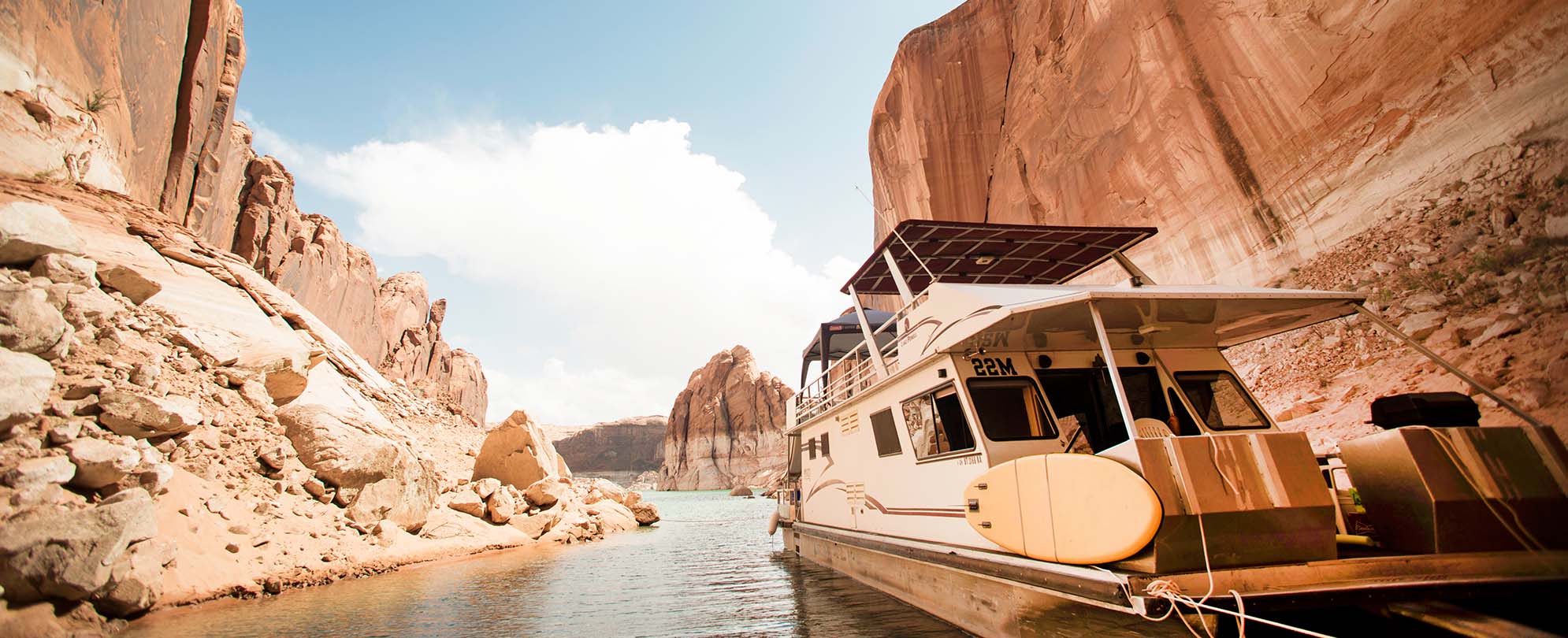 A houseboat floating by red rocks.