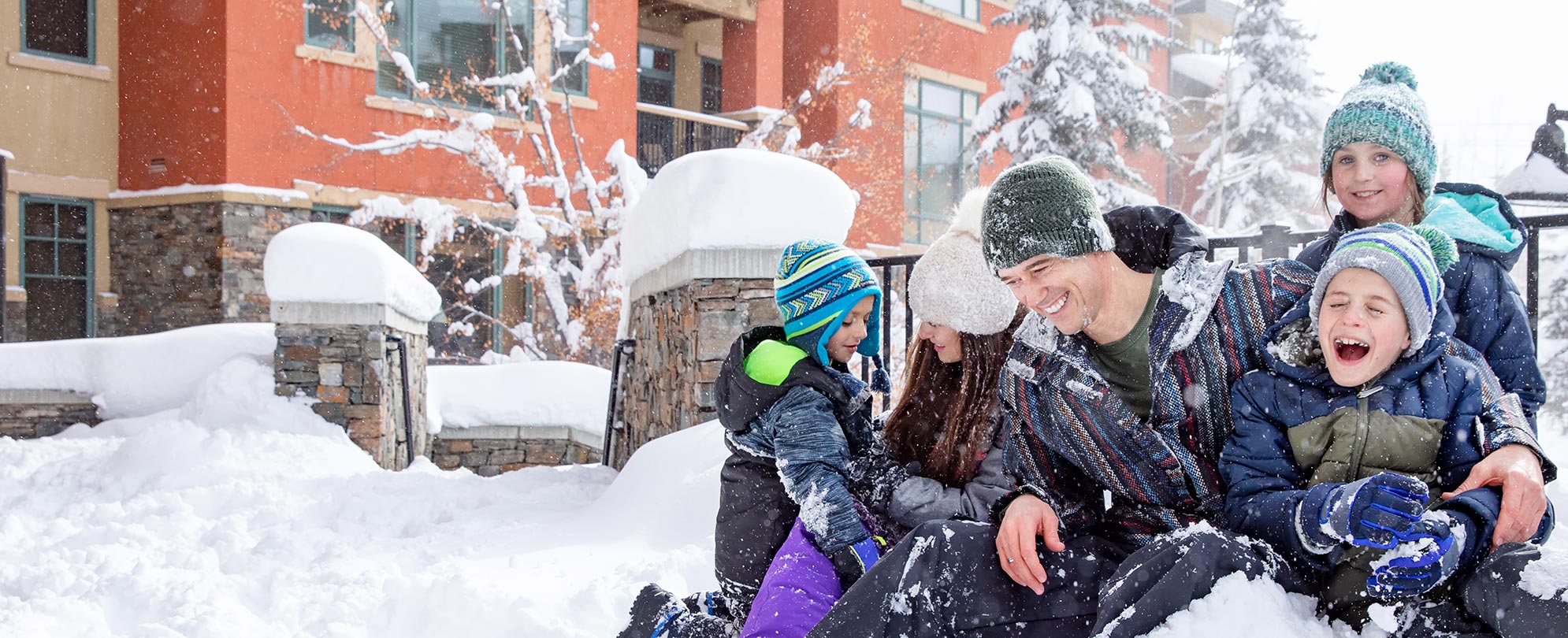 A family of five plays in the snow in front of WorldMark Park CIty resort in Utah