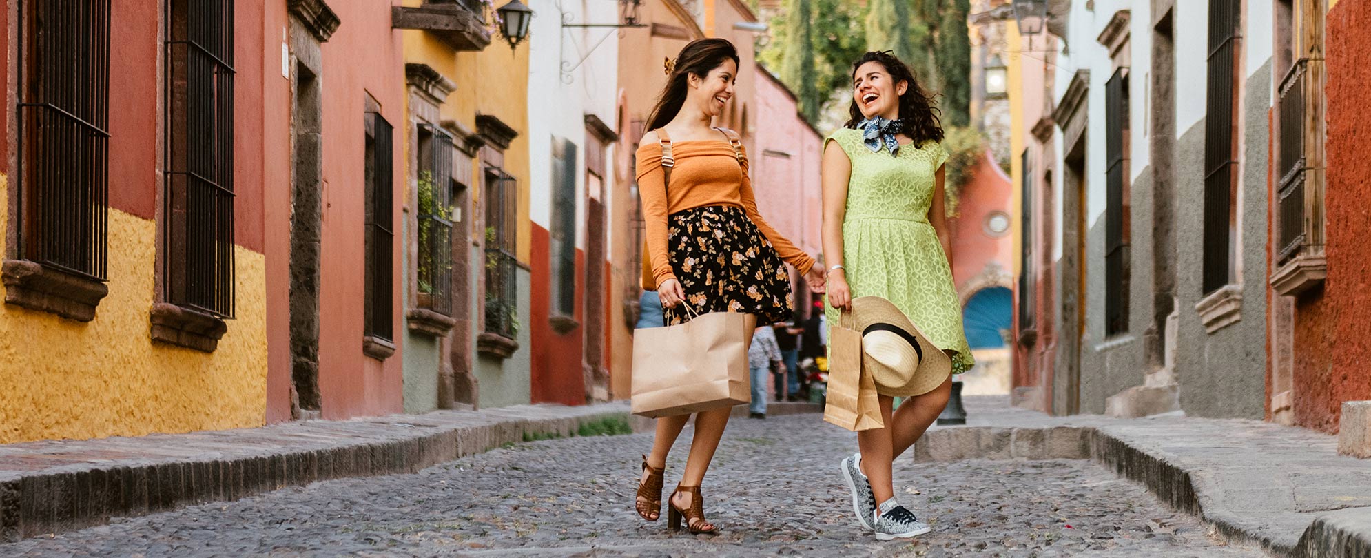 Two women walking down a cobble stone street. 