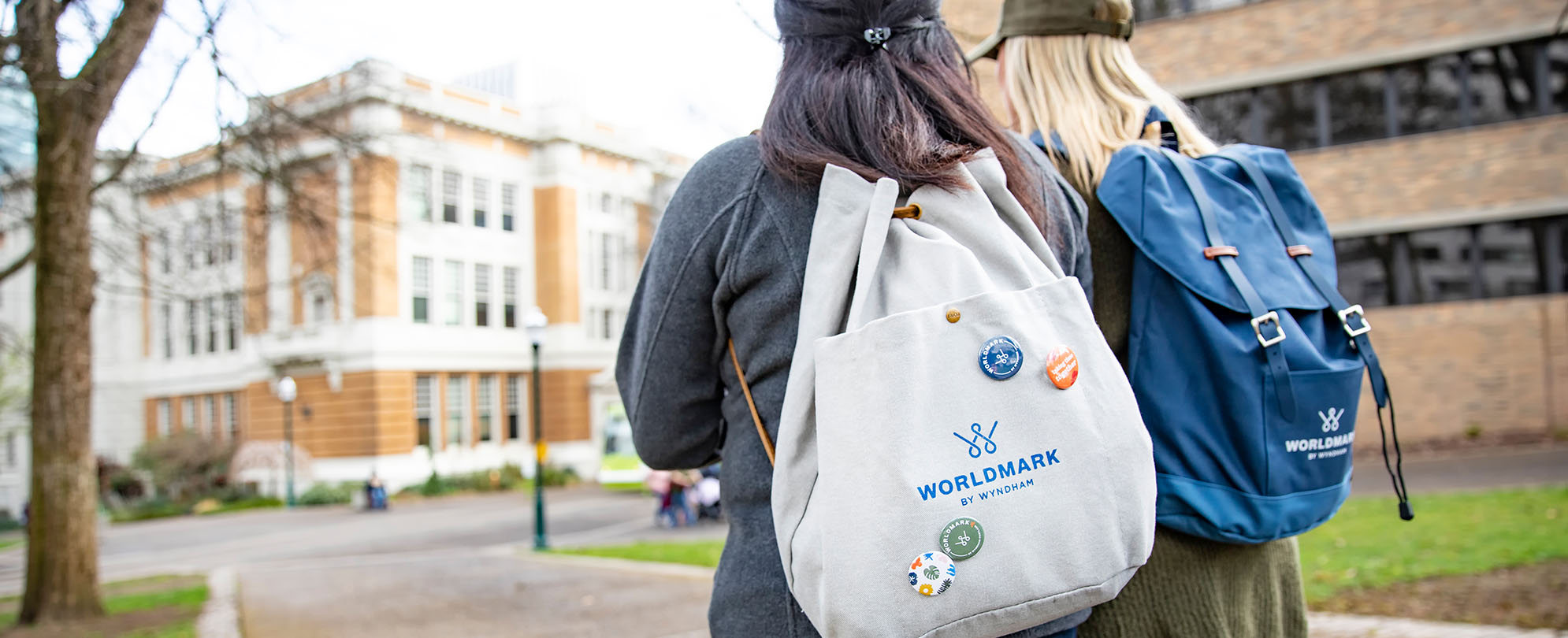 Two women walking on a sidewalk wearing WorldMark by Wyndham backpacks