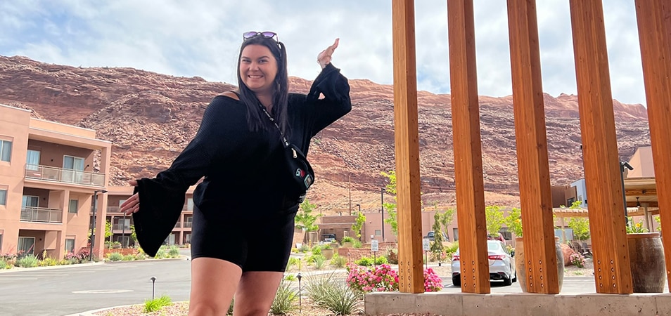 A woman poses with arms angled out in front of the main entrance at the WorldMark by Wyndham resort in Moab, Utah.