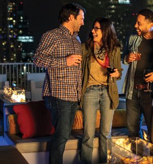 Two couples holding drinks and enjoying the evening at the rooftop lounge of a WorldMark by Wyndham resort.