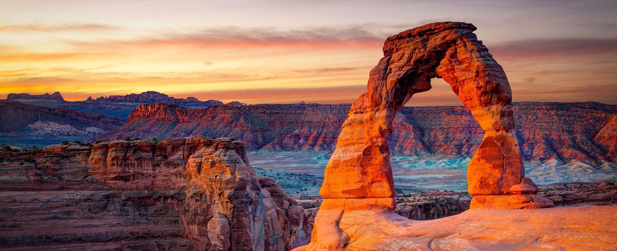 The sun sets over a natural rock arch in Arches National Park and near WorldMark by Wyndham resort in Moab, Utah.
