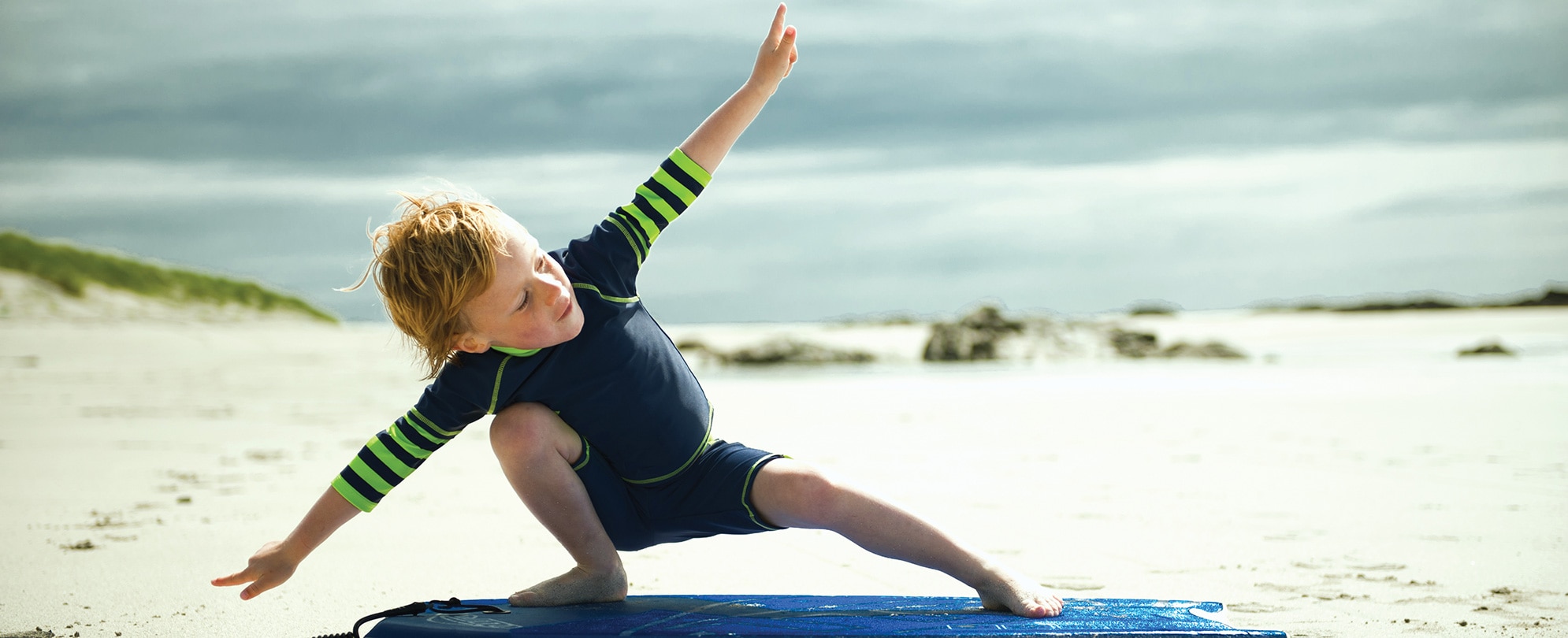 A little boy pretends to surf on the beach during his WorldMark vacation.