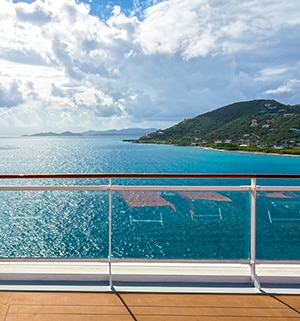 View from a cruise ship balcony overlooking the ocean and the hilly islands of the Caribbean
